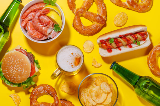 一张生动的照片，展示了一杯啤酒，周围是各种小吃和快餐。图片下载