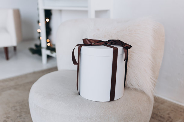 圣诞快乐，节日快乐。时尚的包装大圣诞礼物，带着蝴蝶结放在扶手椅上，家居装饰。图片下载