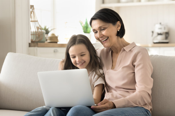 祖母和小孙女一起用笔记本电脑上网。图片下载