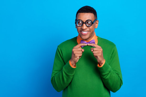 特写照片，展示一个时尚、积极、兴奋的谦虚男孩，手指交叉，微笑着，目光专注，背景为蓝色，空旷无物。图片下载