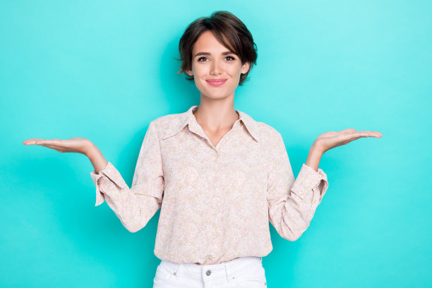 年轻迷人的可爱女孩办公室工作人员在青绿色背景下选择两种不同的产品的肖像照片图片下载