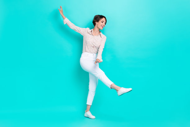 全身照，迷人梦幻的闪亮女性穿着时尚服装，享受舞蹈爱好，放松休息，背景为青色。图片下载