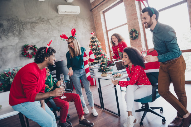 年轻团队员工在办公室室内庆祝，享受温馨的圣诞装饰和聚会乐趣。图片下载