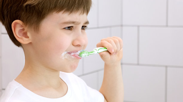 一个可爱的小孩在刷牙。绿色的牙刷。白色浴室中的日常早晨卫生程序。美丽的6岁白人男孩的肖像。刷牙概念。留白。特写镜头。图片下载