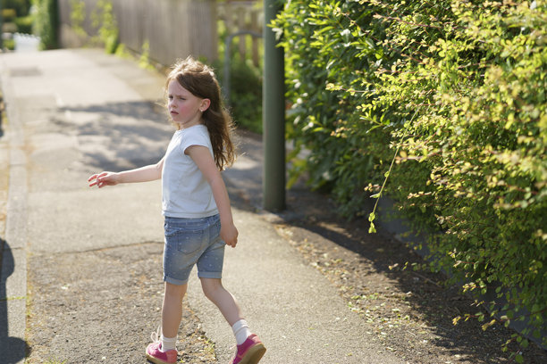 小女孩背对镜头走在欧洲城市的人行道上，长长的金发随风飘扬。儿童旅行概念。图片下载