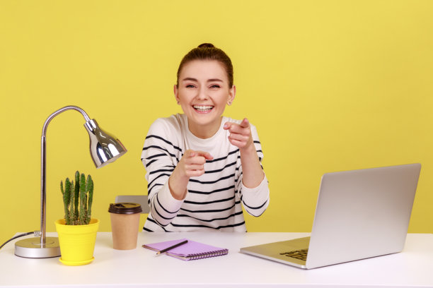 穿着条纹衬衫指向镜头并真诚地笑着的乐观女经理图片下载