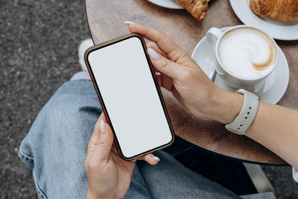 咖啡店里，女性手持白色空白屏幕的智能手机，移动应用设计与广告，在线营销图片下载