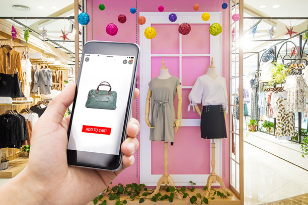 拿着手机在购物中心服装店网上购物图片下载