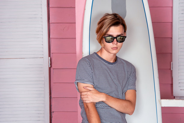 海上假期：在海滩上拿着冲浪板的年轻有魅力的男人图片下载