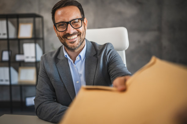 微笑的商人在办公室里伸出手递上信封的特写镜头图片下载