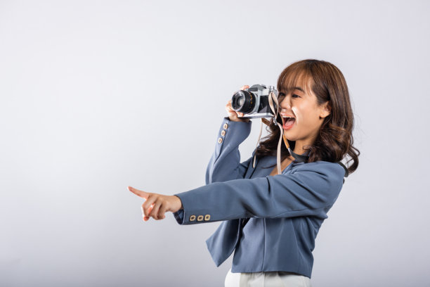 充满活力的快乐亚洲年轻女商人拿着老式相机指向一侧图片下载