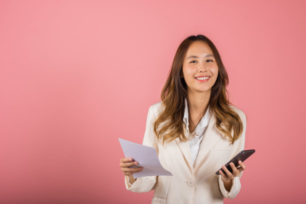 亚洲年轻女性微笑着，手中拿着纸质账单和手机支付二维码，进行账单计算，工作室拍摄的单人肖像。图片下载