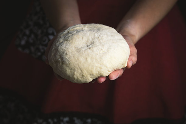 女人的手在厨房台面上捏面团，温馨的家庭烘焙过程照片。图片下载