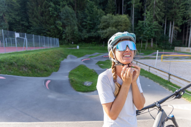 女性在户外自行车赛道上调整头盔带图片下载