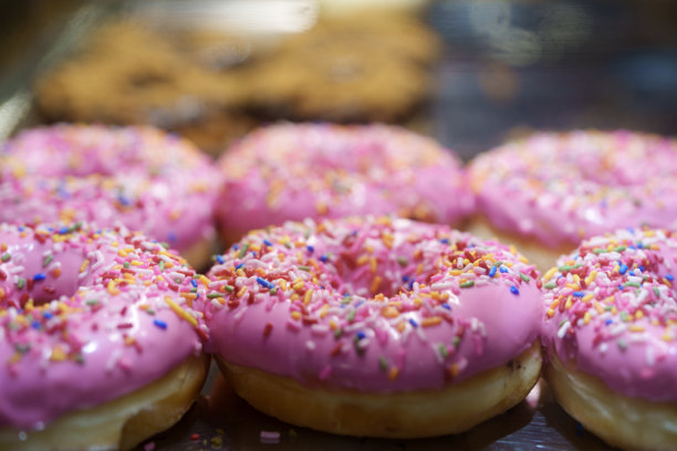 面包店货架上出售的甜甜圈特写图片下载