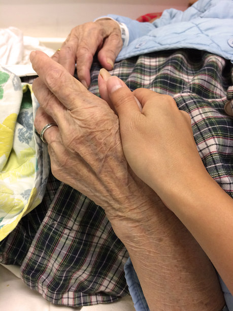 裁剪后的图片:躺在床上的女人握着祖母的手图片下载