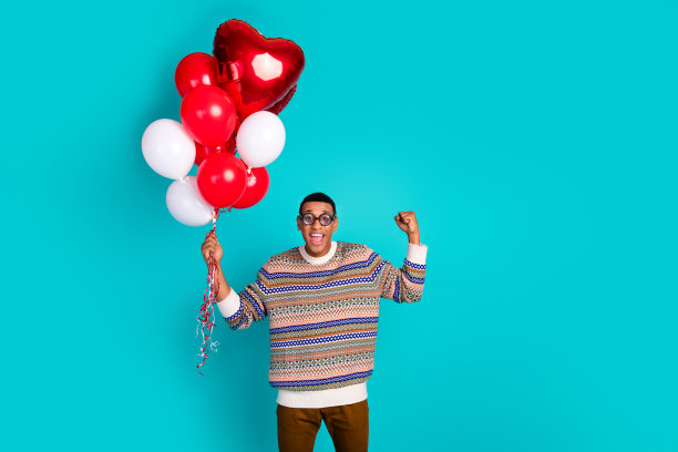 年轻男人举拳拿着气球的竖版照片，蓝绿色背景图片下载