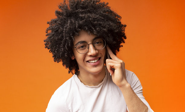 帅气的黑人男子在橙色背景下打电话图片下载