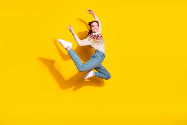 穿着时尚针织保暖服装的漂亮年轻女子在黄色背景下跳舞的芭蕾舞者肖像照片图片下载