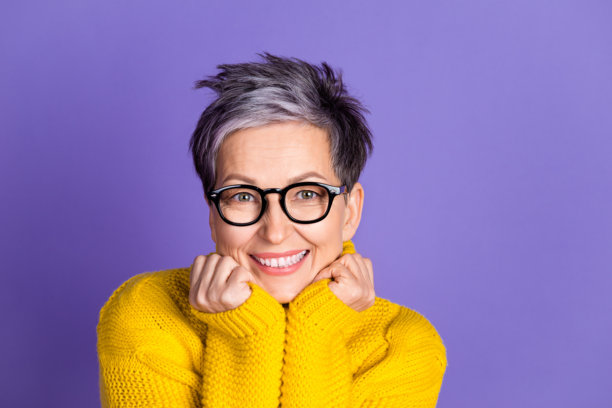 可爱的退休女士的照片肖像，梦幻般的双手托着脸颊，穿着时尚的黄色服装，背景为紫色。图片下载