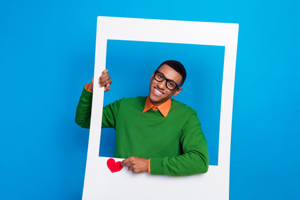 年轻积极成功的影响者博主的特写照片，纸质相框中点击点赞符号，受欢迎的男性，背景为蓝色。图片下载