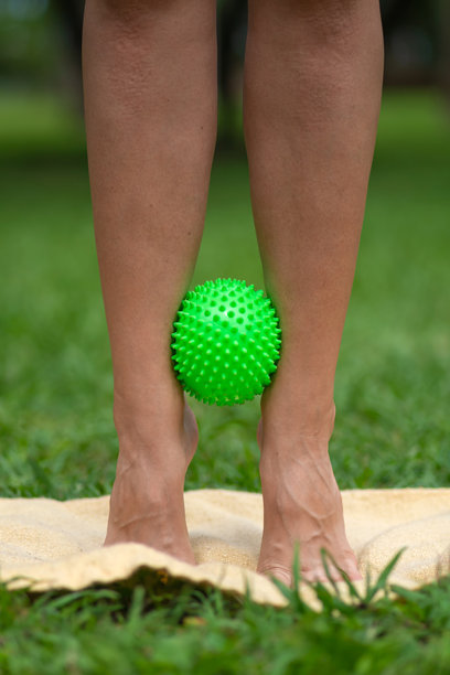 腿部特写，使用按摩刺球进行增强踝关节的锻炼。在公园训练。竖版照片图片下载