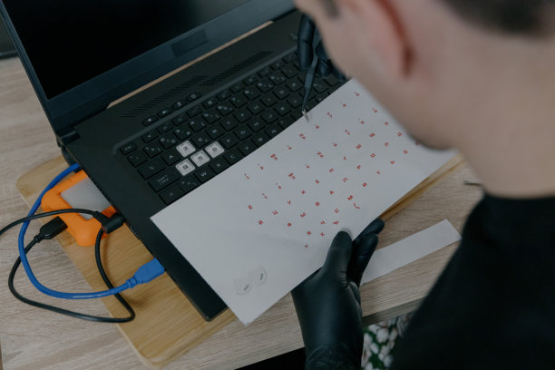 年轻男人用镊子撕掉笔记本电脑键盘上的贴纸图片下载