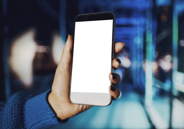 夜景城市中，女人的手握着一部屏幕空白的智能手机特写镜头图片下载