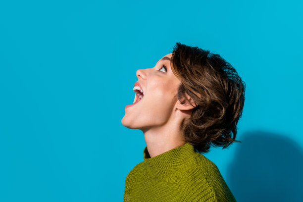 照片中开朗快乐的女孩穿着时髦的衣服，张开嘴尖叫，抬头看空横幅孤立的青色背景图片下载