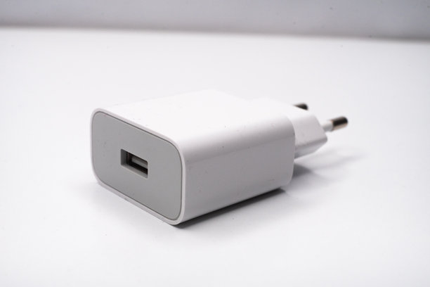 白色智能手机充电器放在白色底座上。图片下载