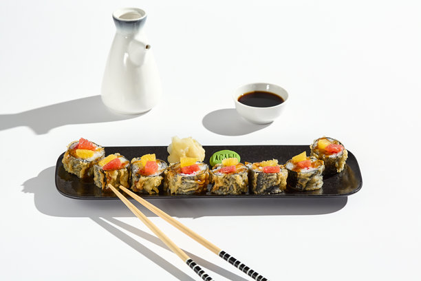 葡萄柚和三文鱼天妇罗卷，清新、色彩鲜艳的寿司，搭配简约的盘子、酱油和芥末。图片下载