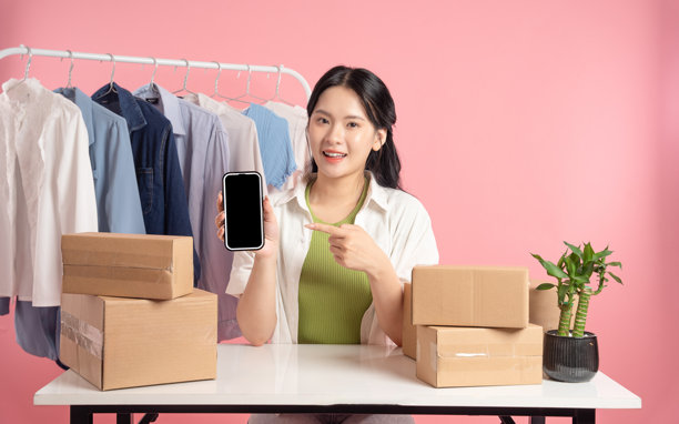 年轻女性商人在粉色背景下在线销售服装的肖像图片下载