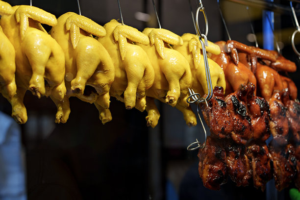 新鲜烤制和蒸制的鸡肉悬挂在当地的食品摊位上。鸡肉整齐地排列着，准备好为热切的顾客提供服务。图片下载