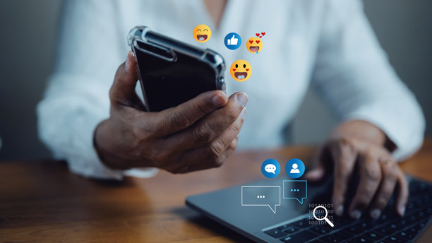 一位女性坐在家中使用智能手机在线聊天，参与社交媒体世界的互动，体现现代科技与数字沟通的概念。图片下载