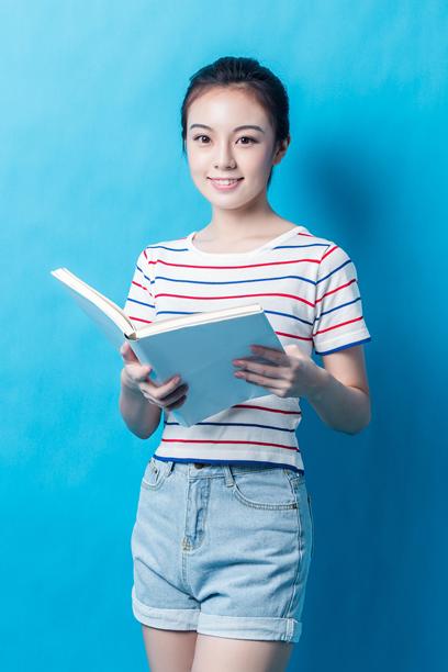 微笑的年轻女性在阅读一本书的肖像图片下载