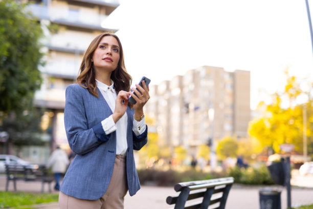 在公园里使用手机的时尚中年妇女图片下载