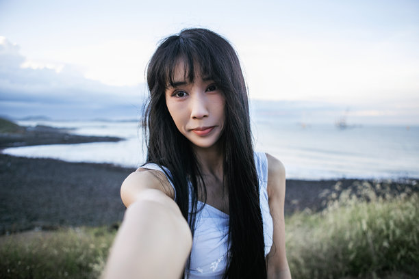 一个亚洲女孩在海滩拍摄视频博客并在社交媒体上分享。图片下载