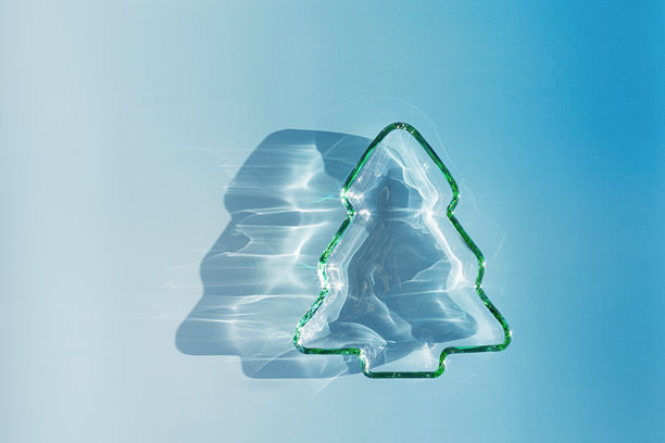 阳光下绿色玻璃圣诞树，具有阴影和光晕的冬季概念照片图片下载