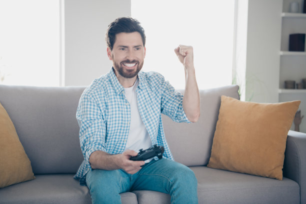 英俊的成熟男子独自玩PlayStation游戏机，手持操纵杆赢得比赛的照片图片下载