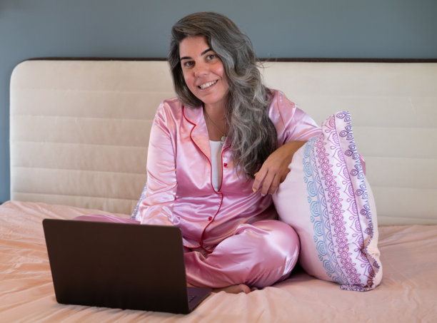 怀孕的女商人在床上穿着睡衣用笔记本电脑工作图片下载