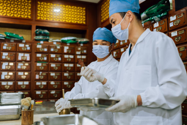 中医系列。年轻的中药学徒向年长的中药师学习如何制作中药。图片下载