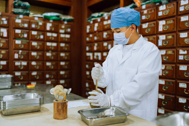 传统中医系列。年轻的中药学徒正在调配药材。图片下载