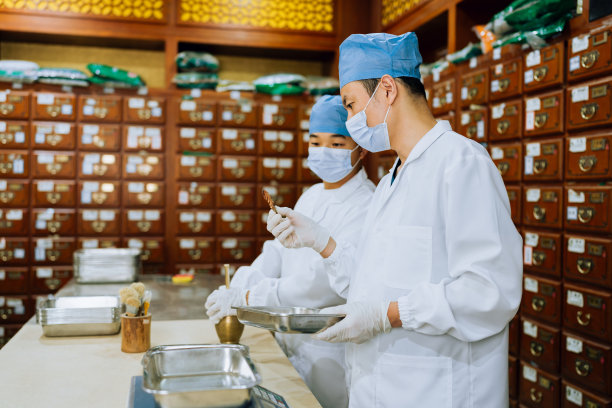 传统中医系列。年轻的中药学徒向年长的中药师学习如何制作中药。图片下载