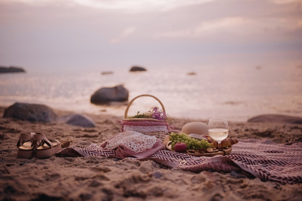 美丽的夏季海滩日落野餐，享用白葡萄酒、可颂面包、奶酪和新鲜水果。图片下载