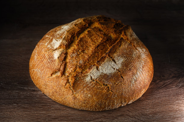 传统的发酵酸面包，外皮粗糙，放在乡村风格的木桌上。健康食品摄影图片下载