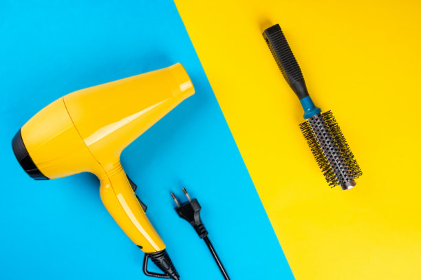 蓝色背景上的黄色吹风机和黄色背景上的蓝色造型梳。图片下载