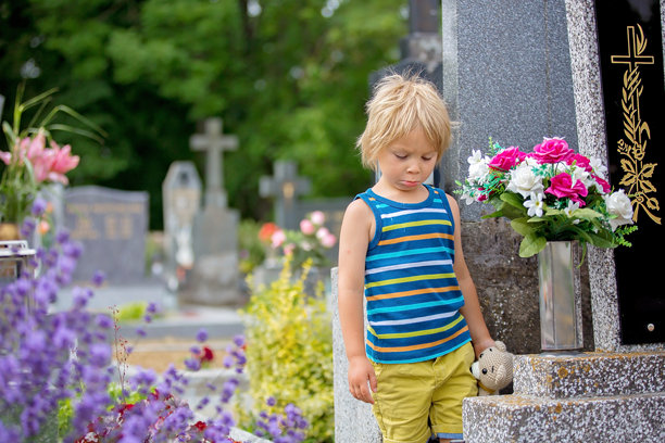 小男孩坐在墓地上，感到伤心图片下载