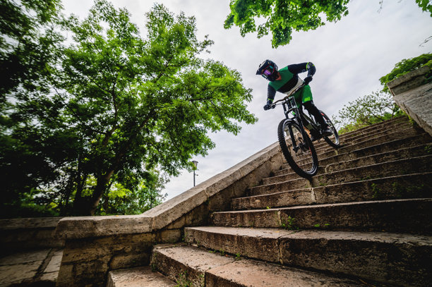 男性自由骑行者骑自行车快速下坡，穿过树木之间的老旧楼梯，享受高速下坡的全景。图片下载