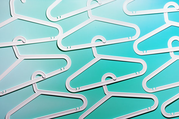 白色塑料衣架和钩子的顶部视图，背景为白色和青色的极简风格图案。平铺展示用于悬挂衣物的衣架。极简趋势照片，生活方式或室内设计概念。图片下载