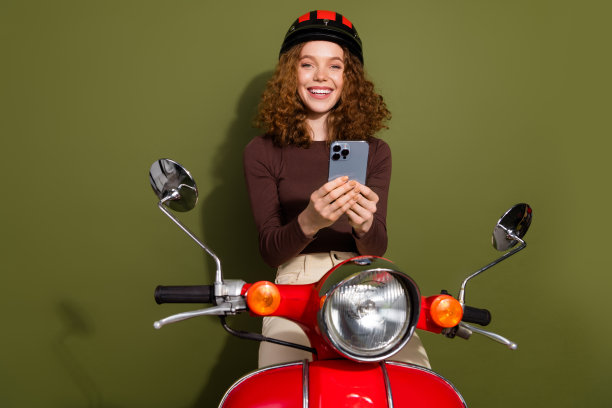 一位穿着棕色服装的光鲜迷人的年轻女士，骑着滑板车，使用现代电子设备，背景为卡其色。图片下载